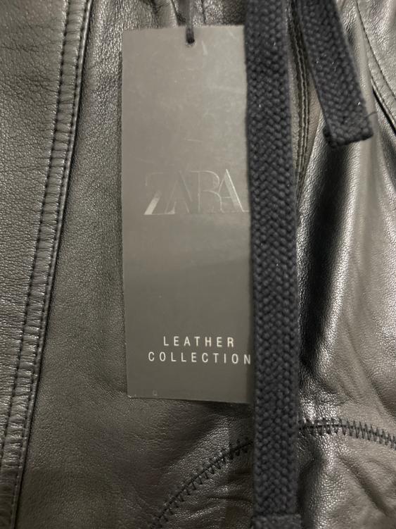 Black Zara label on a black leather garment. Visible text: "LEATHER COLLECTION". Black cord next to the label.