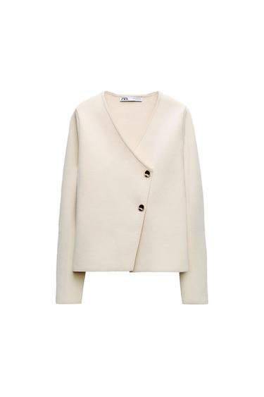 Beige jacket with long sleeves, cross-over fastening and two black buttons. Visible label on the neck with the text "ZARA".