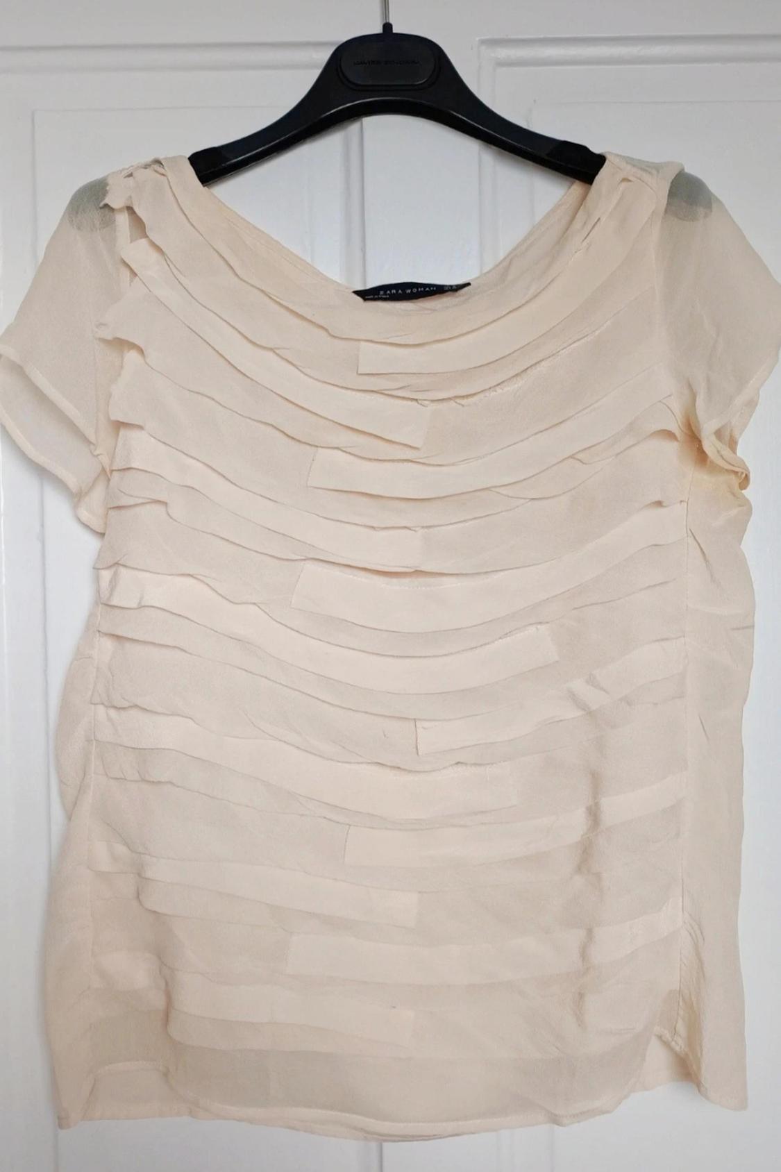 Front view of beige blouse with horizontal layers and short sleeve.