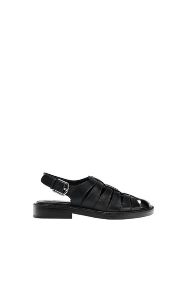 Black leather sandals with interwoven straps and a metal buckle on the heel, against a white background.