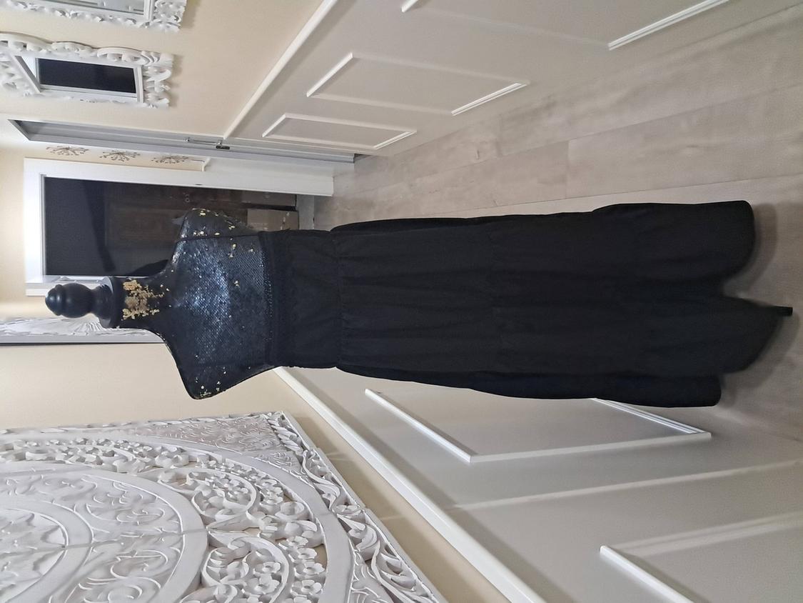 Mannequin in a long black lace dress in a hallway with white walls and decorative white-framed mirrors.