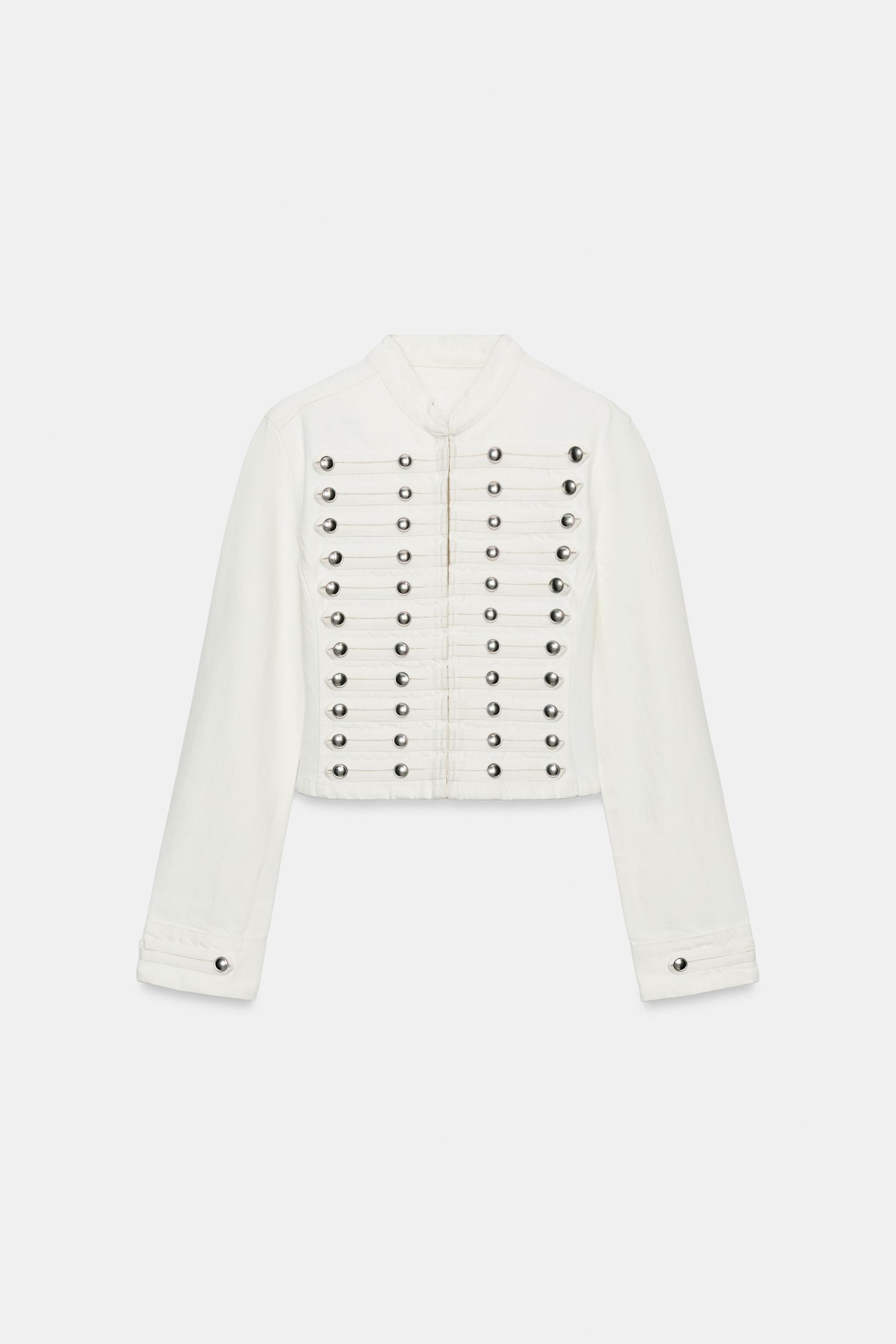 Μπροστινή όψη λευκού σακακιού με διακοσμητικά μεταλλικά κουμπιά σε οριζόντιες σειρές και ψηλό γιακά.