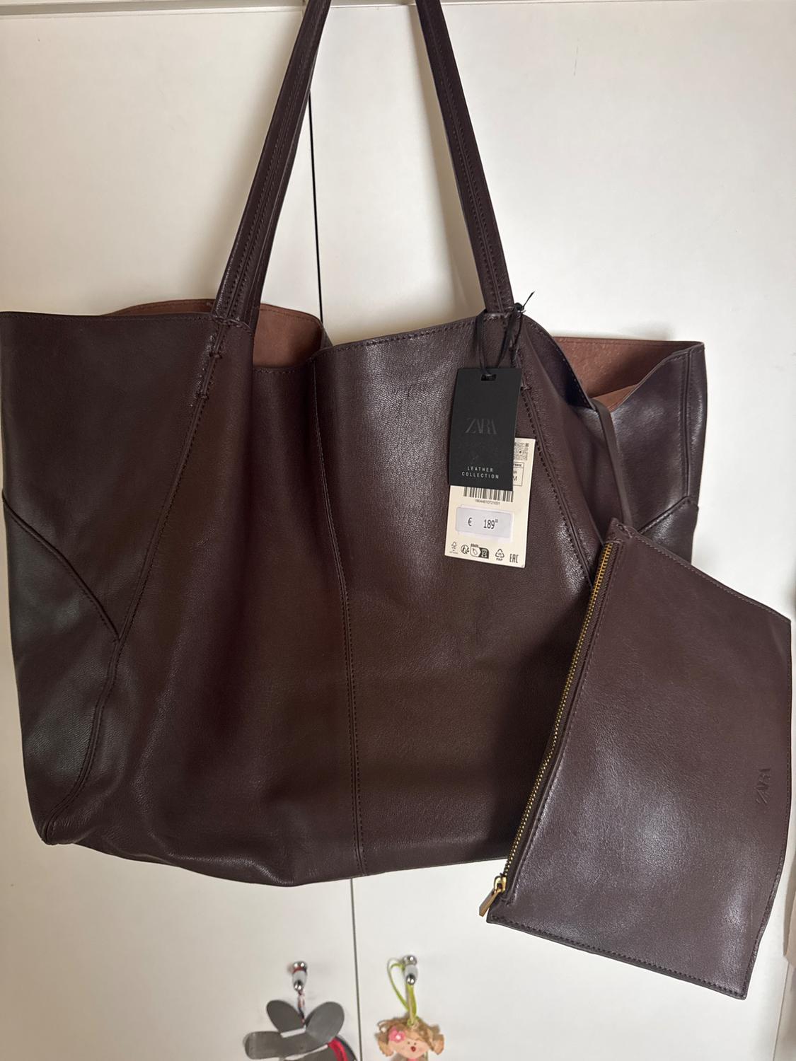 Dark brown leather tote bag and wash bag in a white wardrobe. Text: ZARA LEATHER COLLECTION € 189.