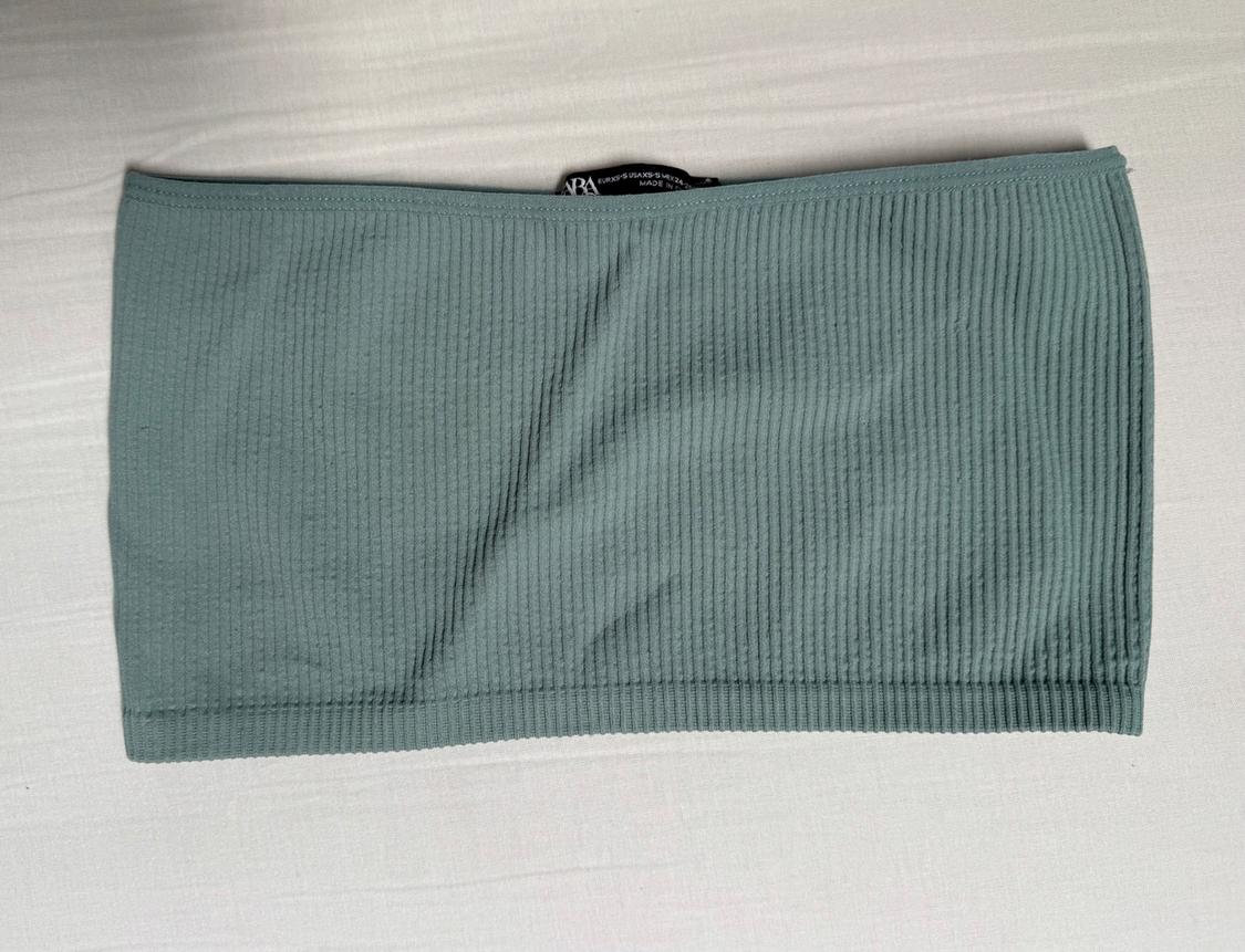 Ribbed tube top in green on a white background. Black label visible at the top.