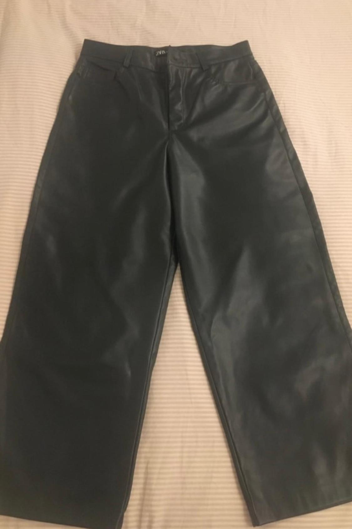 Front view of black trousers with side pockets and front fastening.