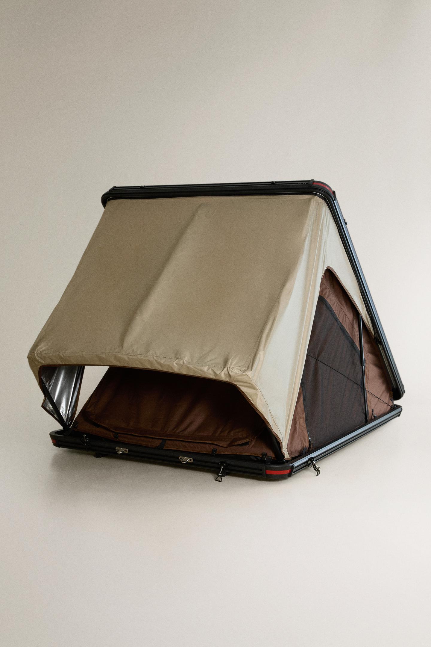 Front view of a roof tent in beige and brown. Elevated structure with a front opening and side mesh window.
