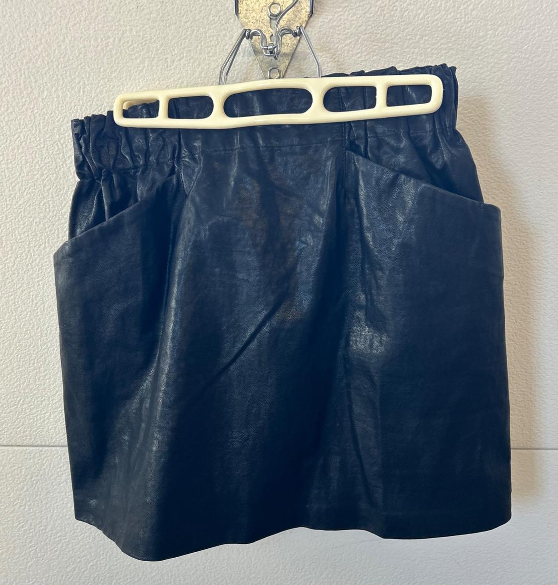 Front view of a black skirt with side pockets and an elasticated waistband.