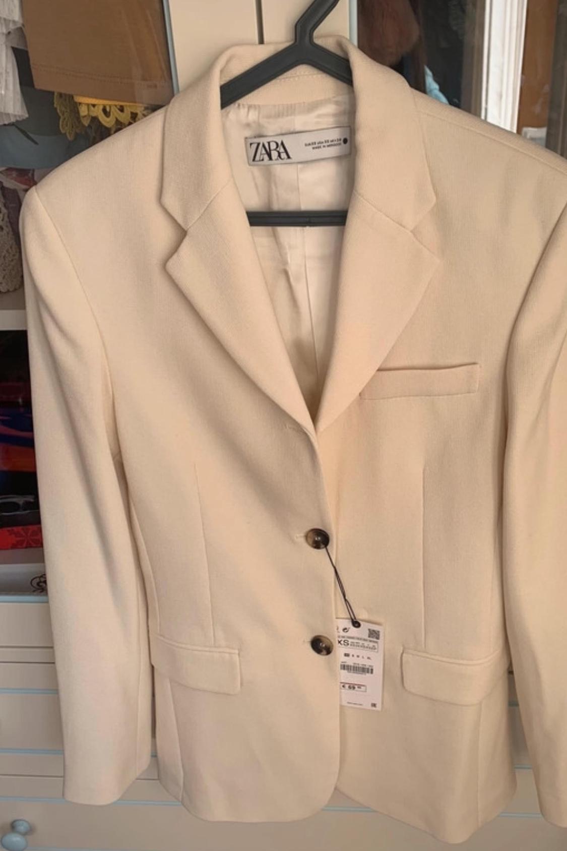 Front view of beige blazer with lapel and front pockets.