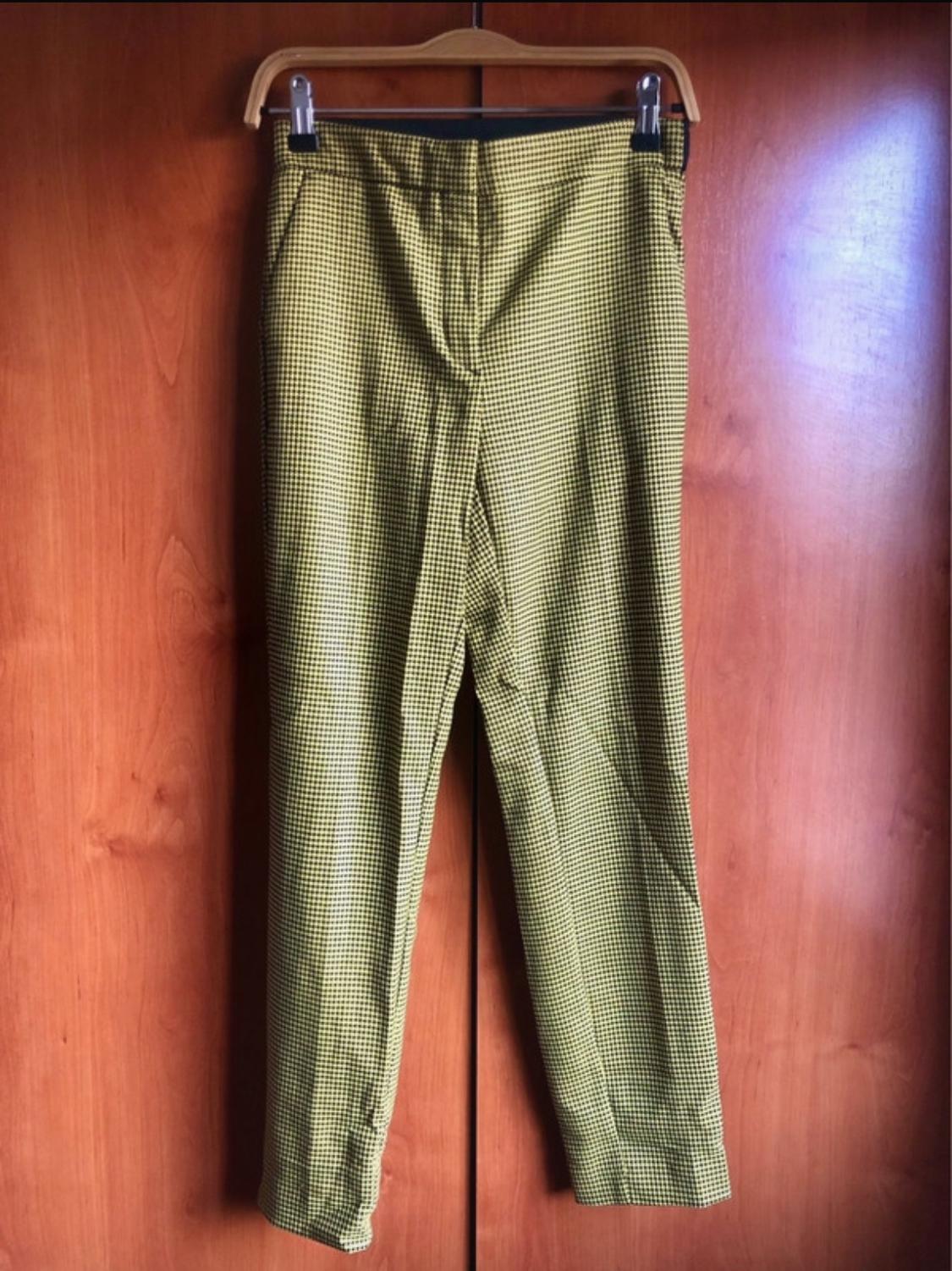 Front view of green and black checked trousers hanging on a hanger.
