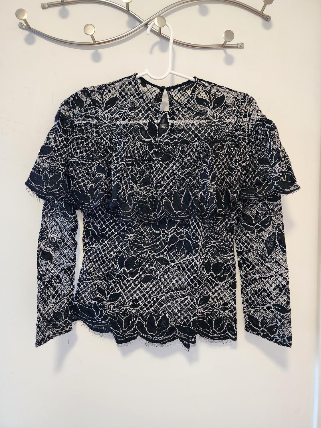 Front view of a black lace blouse with long sleeves and a floral design