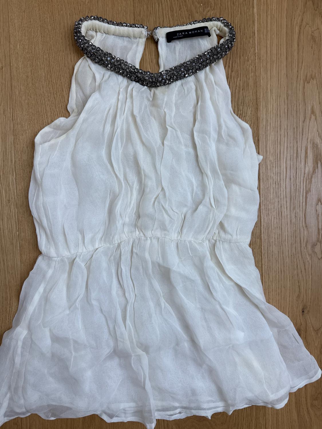 Flowing white top with dark beaded halter neck and elasticated waist on a wooden background. Visible label: ZARA WOMAN.