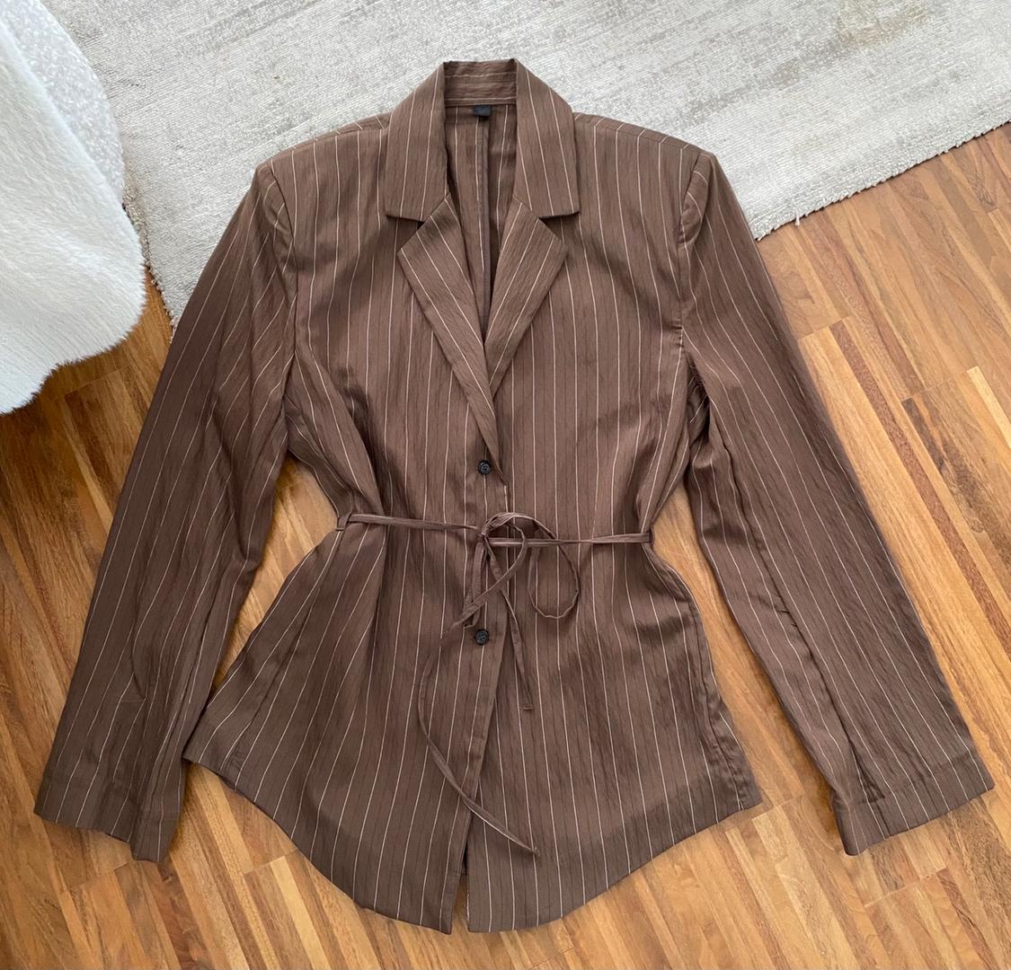 Striped brown blazer with a tie-waist belt, displayed on a wooden floor next to a light-coloured rug.