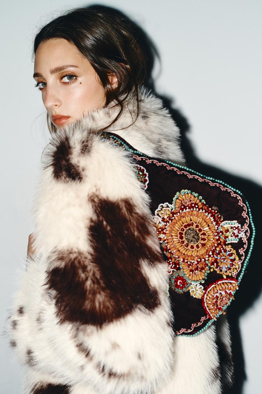 Detail of white and brown coat with colorful floral embroidery on the back.