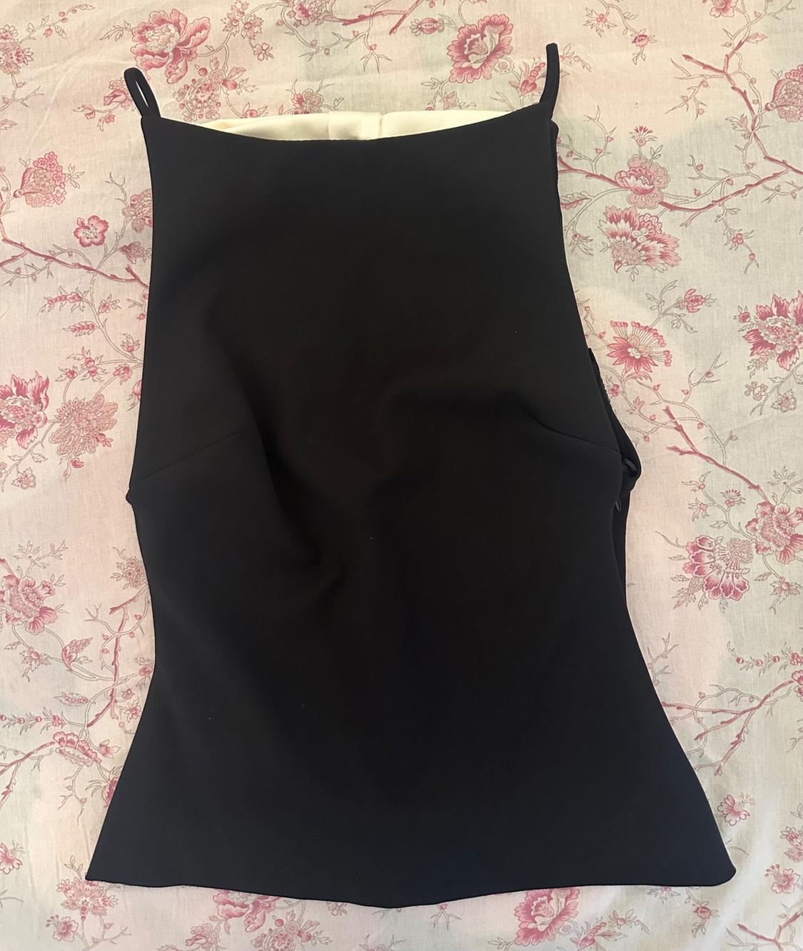 Black sleeveless top on white fabric with pink floral print.