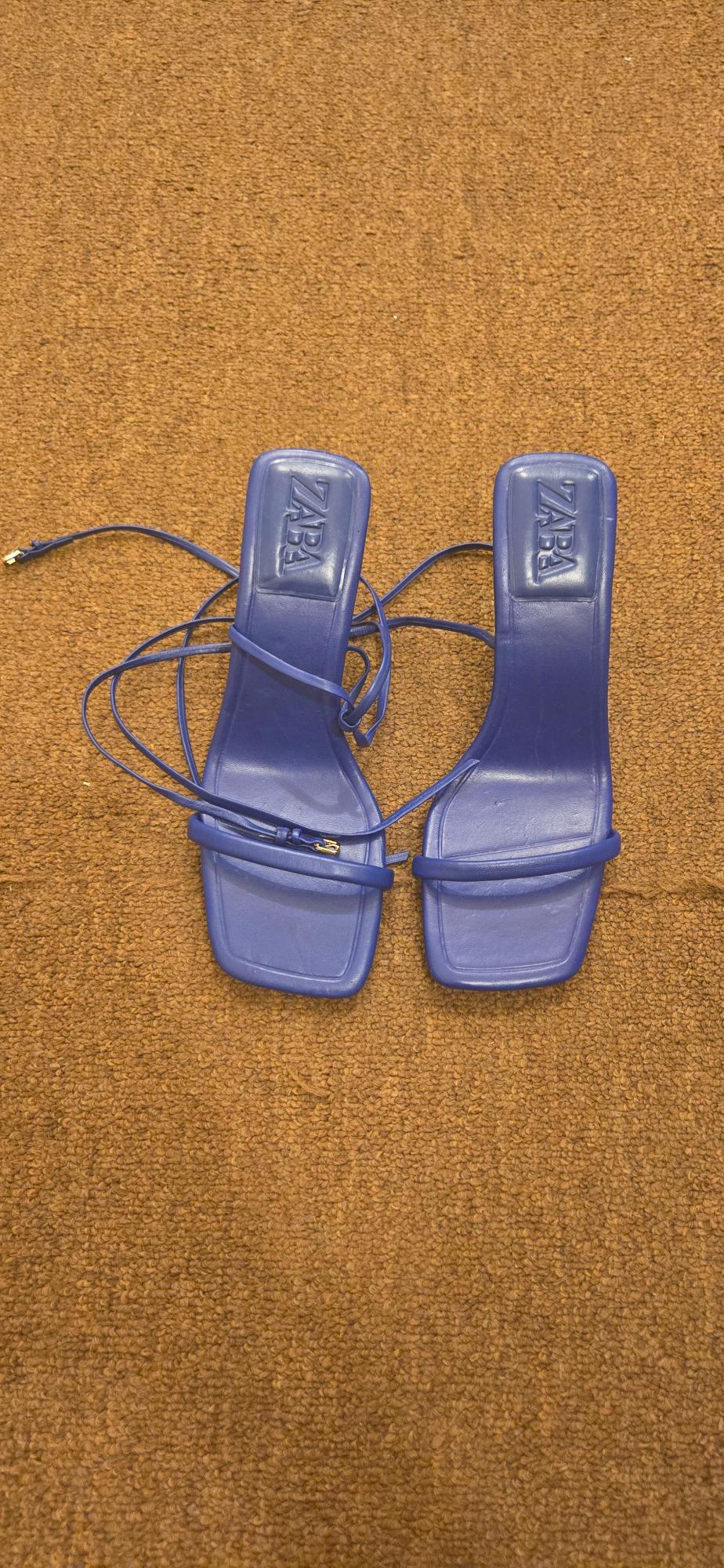Front view of blue sandals with straps and a debossed logo on the insole.