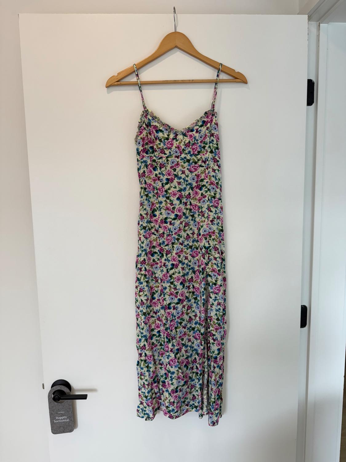 Floral sundress hanging on a wooden hanger over a white door. Label on the door: "Happily horizontal".