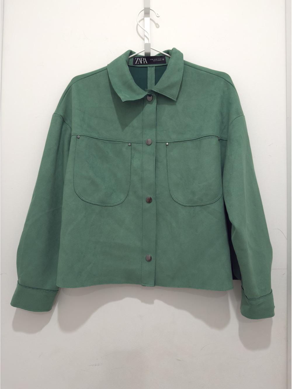 Green Zara jacket with a collar, front buttons, and two large pockets on the chest, hanging on a hanger against a white background.