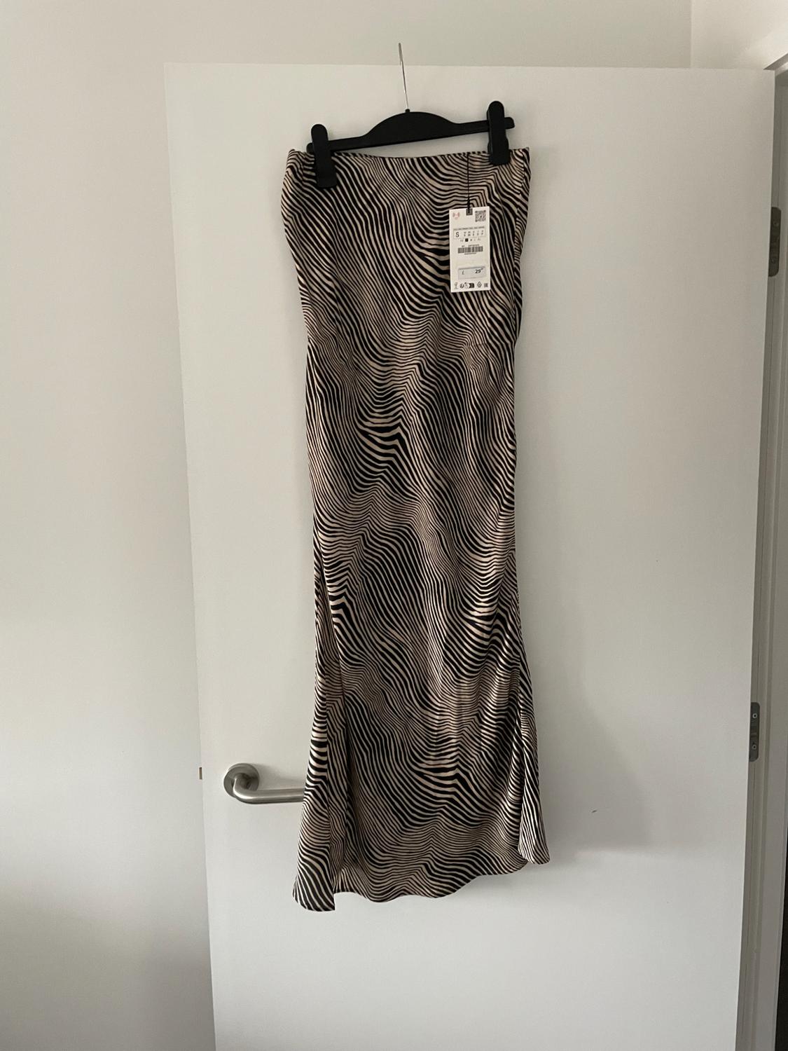 Long skirt with a black and white wavy line print, hanging on a white door with a visible tag.