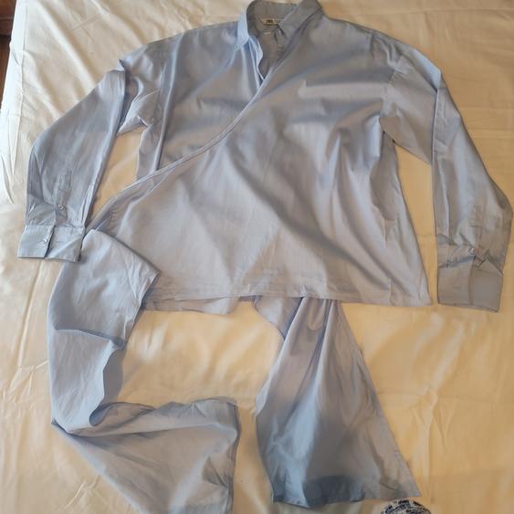 Light blue long-sleeved shirt with an asymmetrical design, spread out on a white surface.