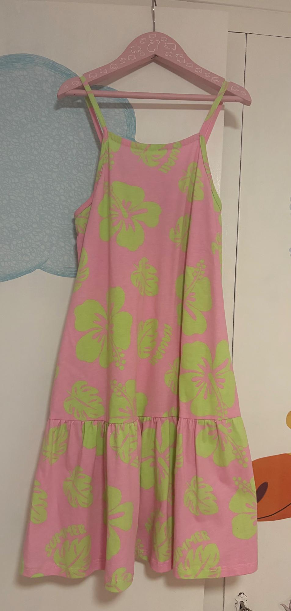 Pink strappy dress with a green floral print and the words HAWAII and SUMMER. Hanging on a coat hanger above a wardrobe with a blue cloud.