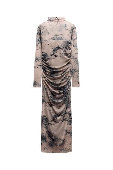 Back view of a long dress with a marbled print in beige and black tones, with ruching in the back.