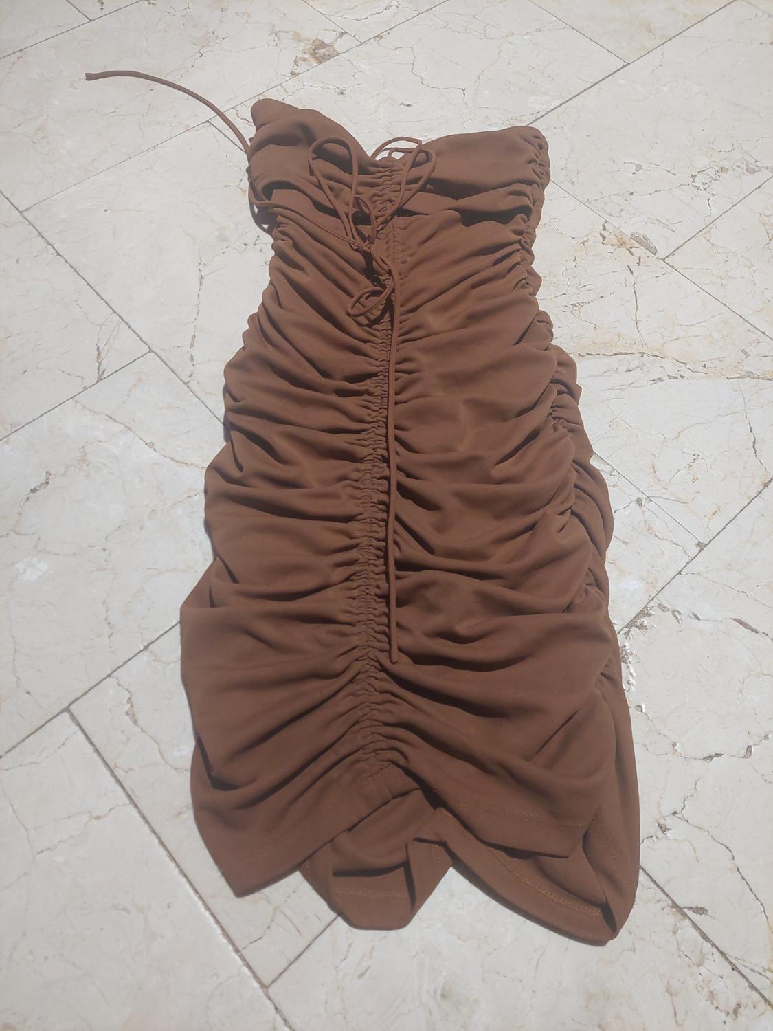 Short brown dress with front ruching and drawstring detail, presented in a relaxed style on a light tiled floor.