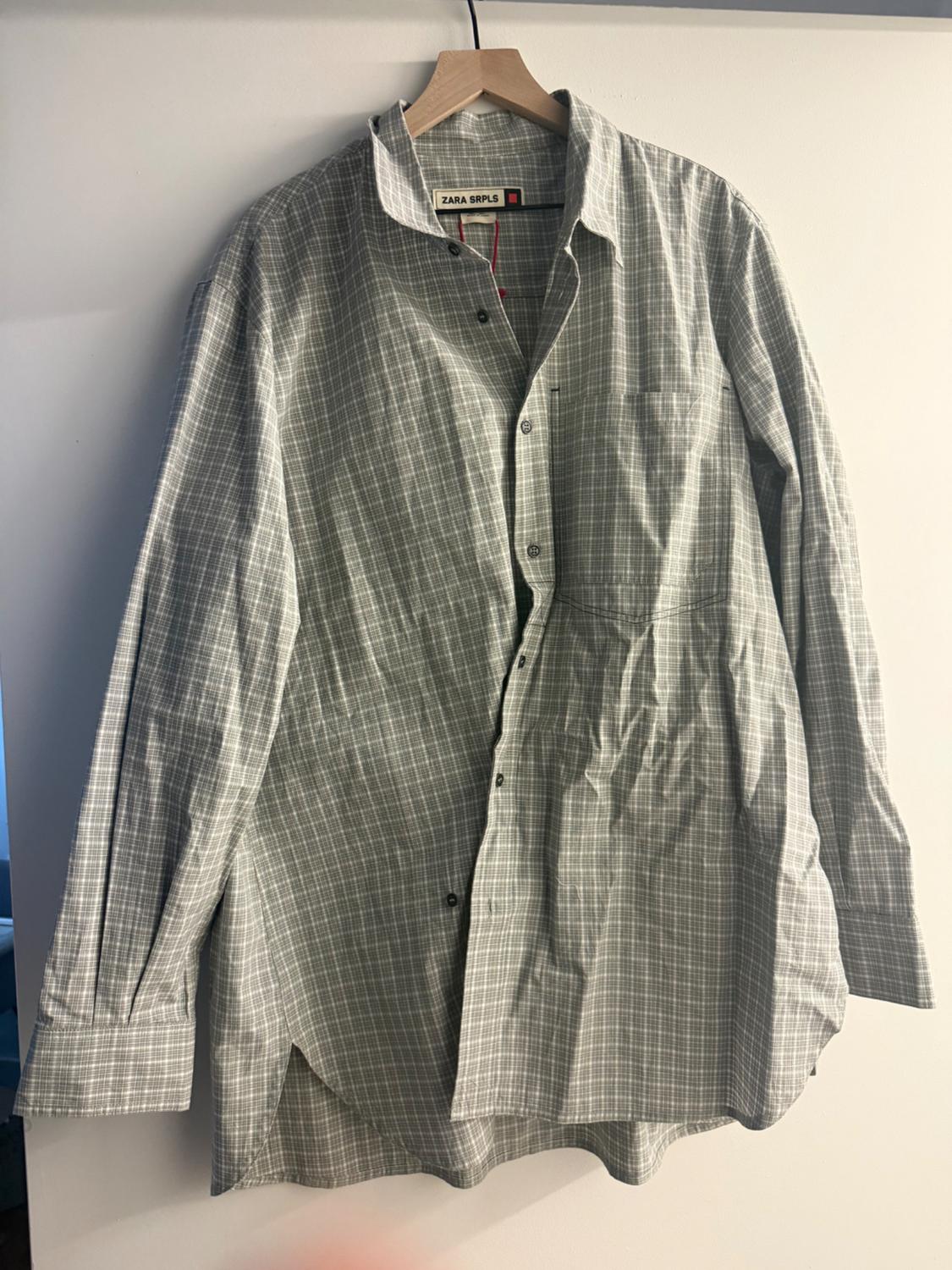 Grey checked shirt hanging on a wooden hanger, with a visible label that reads "ZARA SRPLS".