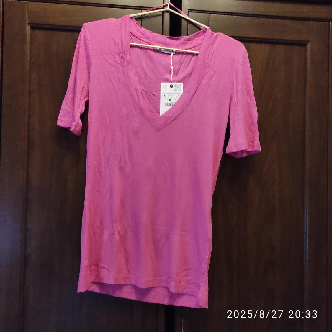 Pink short-sleeved V-neck t-shirt hanging on a hanger. Visible label. Date in the corner: 2025/8/27 20:33.
