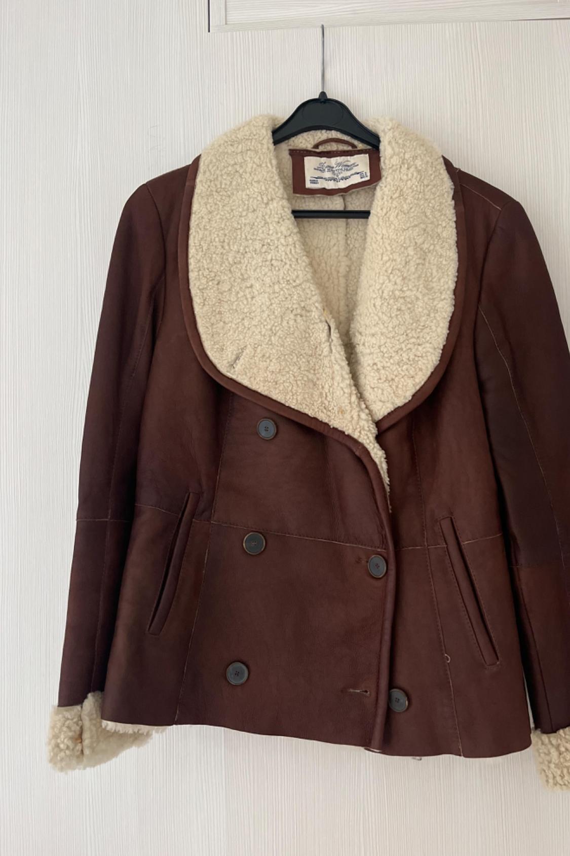 Front view of a brown jacket with a shearling collar and side pockets.