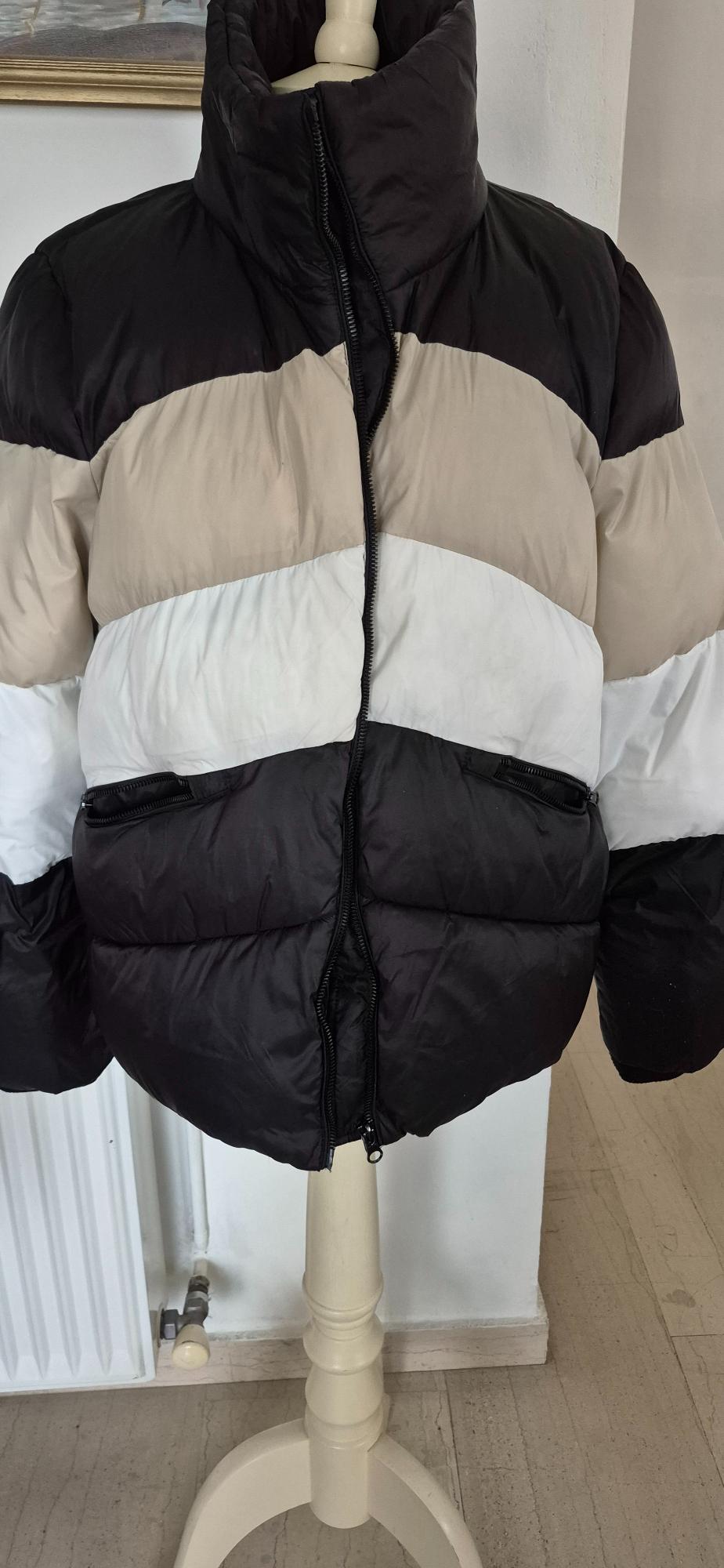 Black, beige, and white striped padded jacket on a mannequin, with front zip and side pockets.