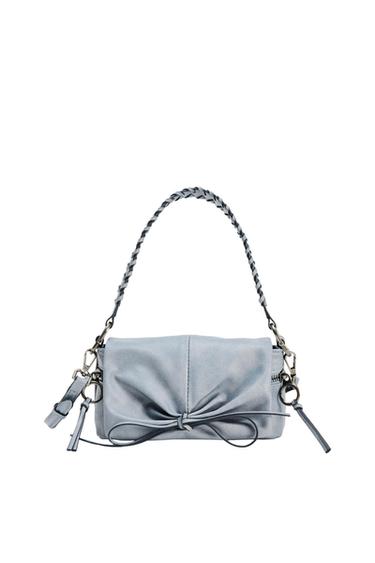 Gray purse with braided handle and decorative bow on the front. White background.
