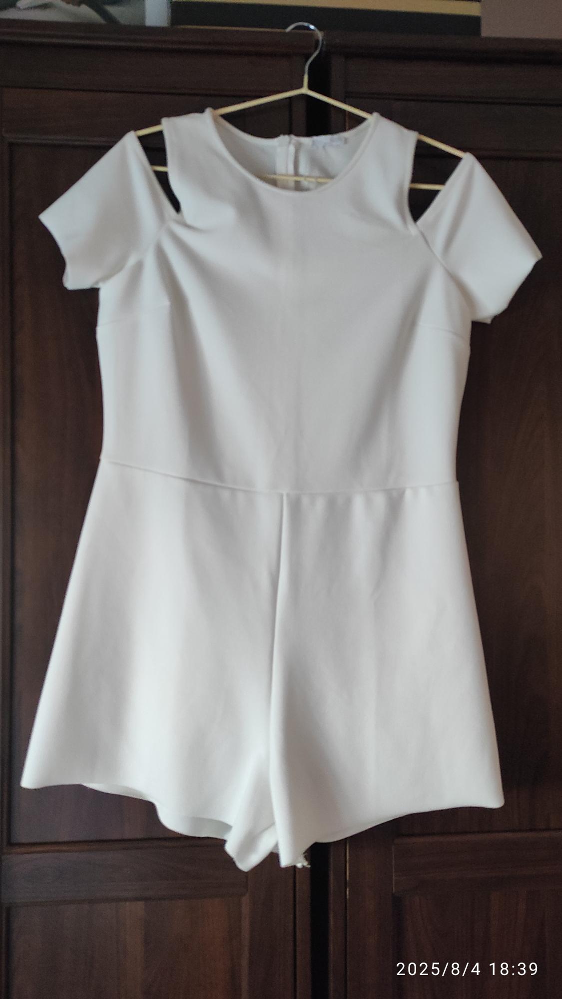 White jumpsuit with off-the-shoulder design hanging on a hanger in front of a wooden wardrobe. Text in the image: "2025/8/4 18:39".