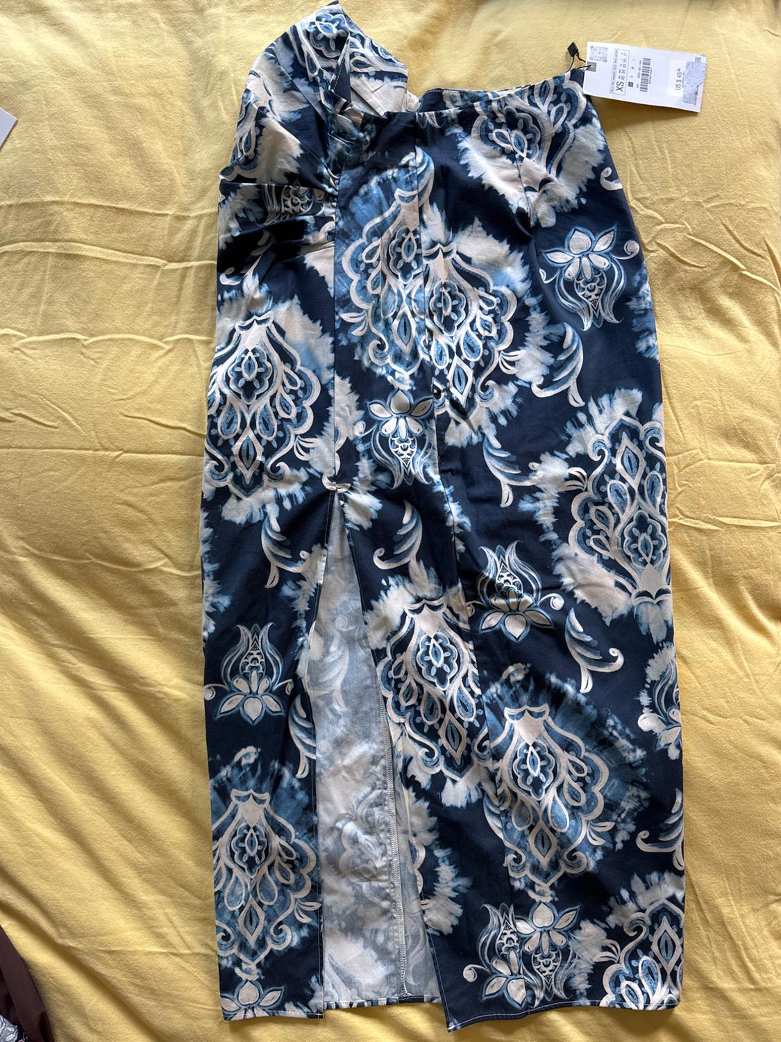 Blue and white maxi skirt with an ornamental print and a slit over yellow fabric. Label with text XS US $45.