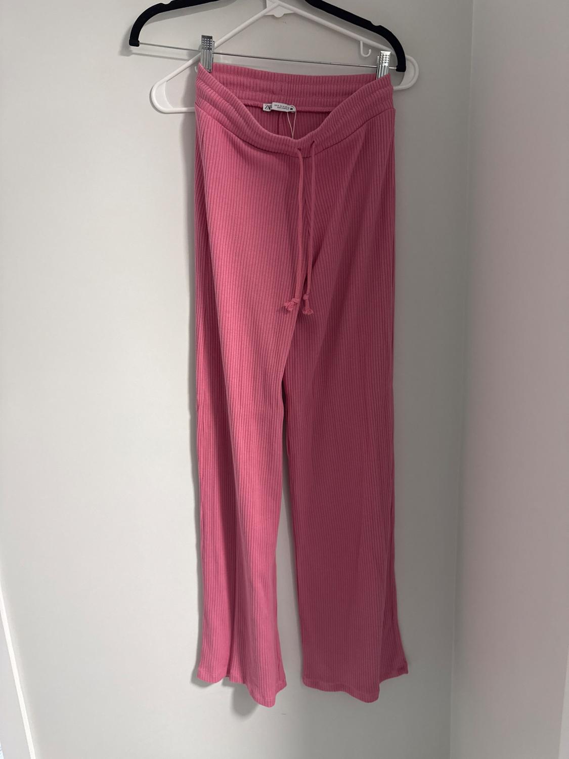 Front view of pink trousers with elasticated waistband and drawstring.