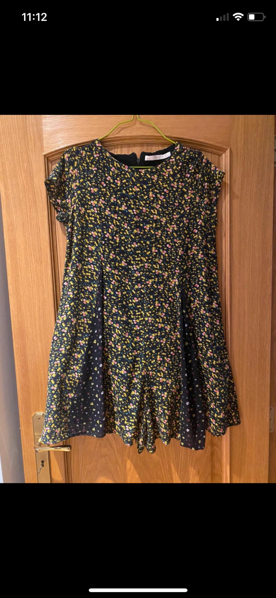 Front view of a floral dress with a small yellow and pink floral print on a dark background.