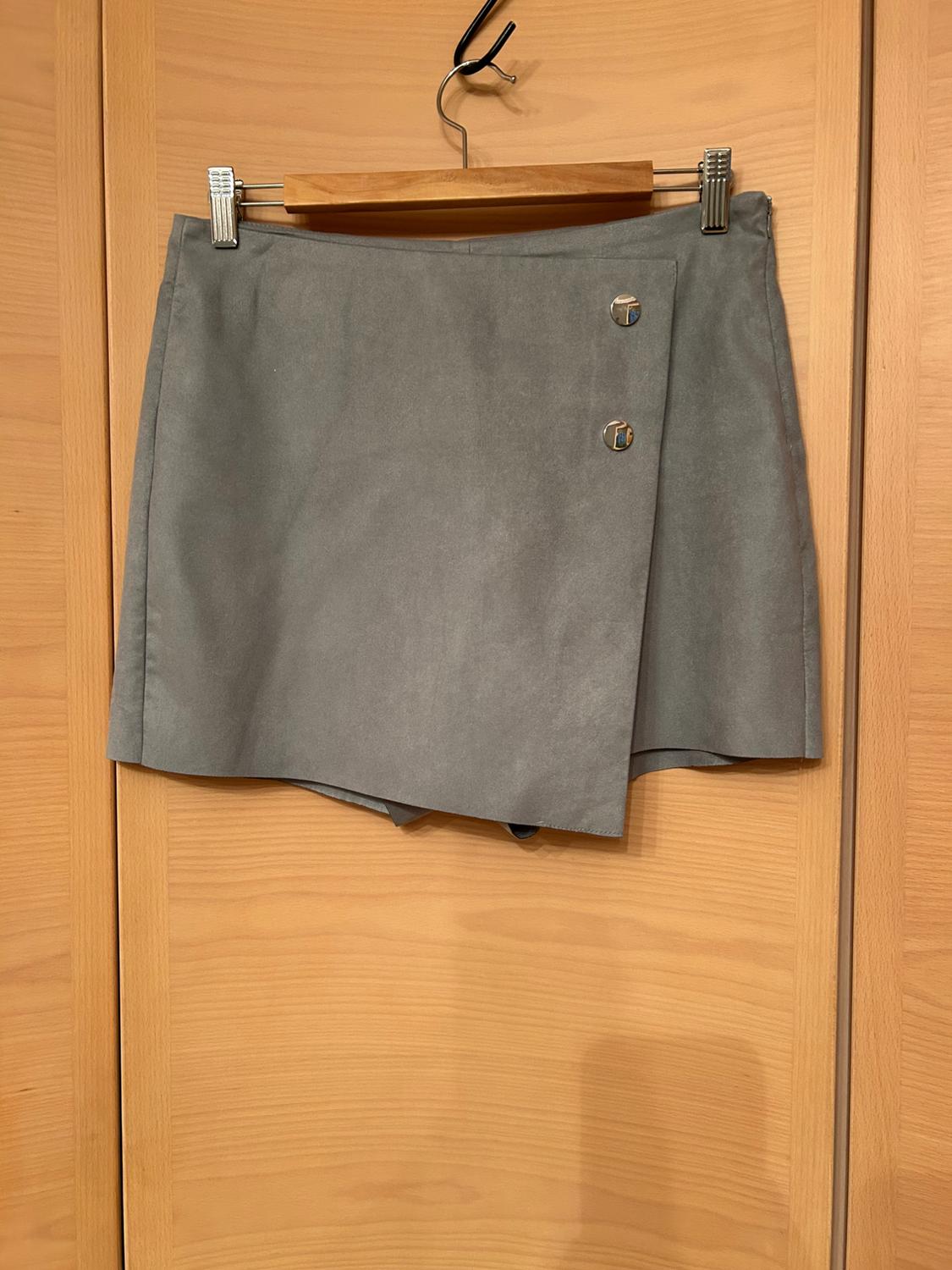 Grey wrap skirt with two metal buttons, hanging on a wooden hanger against a light wood background.