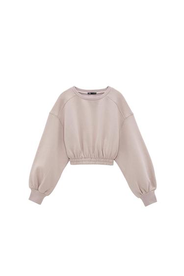 Front view of a beige sweatshirt with puffed sleeves and an elasticated waist.