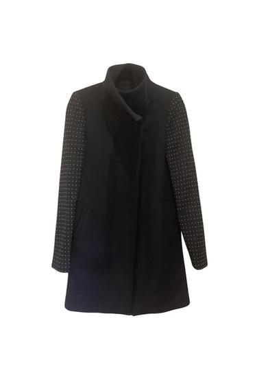 Front view of a black coat with white polka dot sleeves and side pockets.