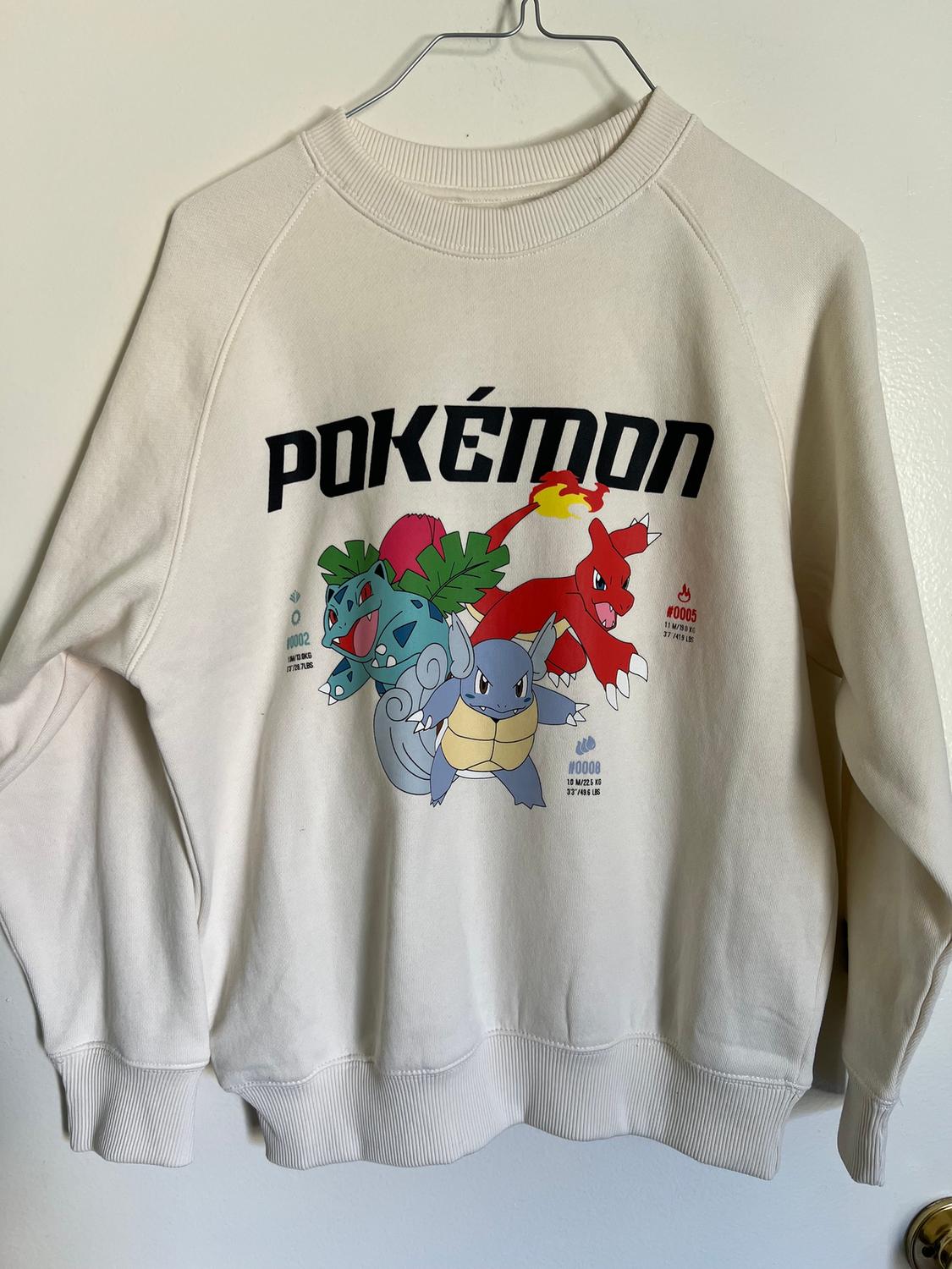 White sweatshirt with a Pokémon print, showing Ivysaur, Charmeleon, and Wartortle. "POKÉMON" text in black on a white background.