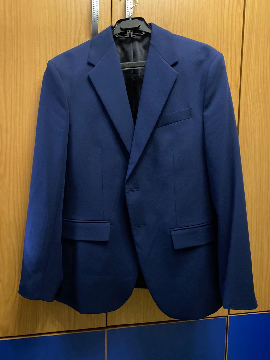 Blue jacket hanging on a black hanger against a light wooden background and blue panels.