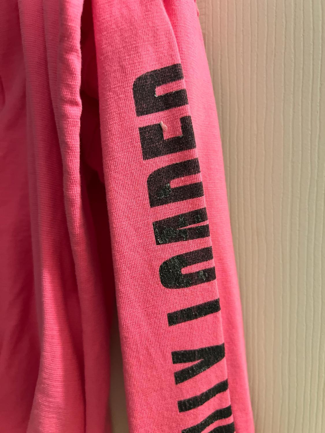Close-up of a pink long-sleeve shirt with the black text HOLLISTER printed vertically.
