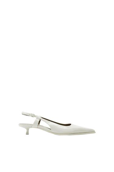 White low-heeled shoe with adjustable heel strap, on a white background. Elegant and minimalist design.
