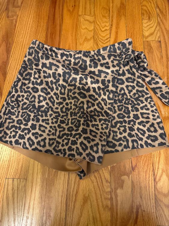 Leopard print shorts on a light brown background, placed on a wooden floor.