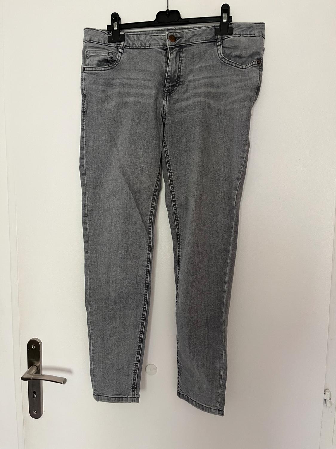 Front view of grey trousers with front pockets and a brown button.