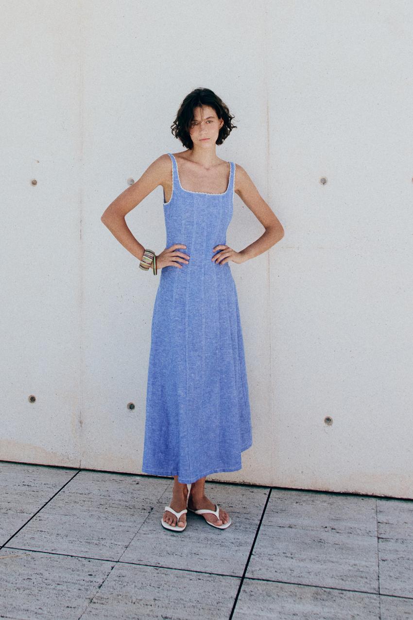 Light blue sleeveless midi dress set with a round neckline, wide lace-trimmed straps, vertical seams, and white sandals.