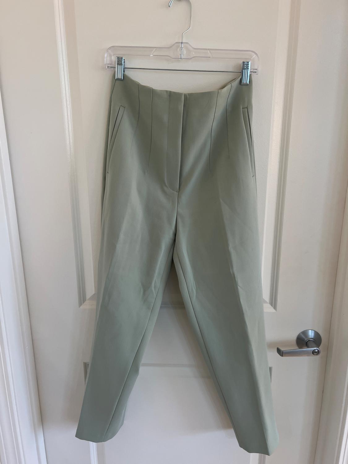 Front view of green trousers with pleats and side pockets.