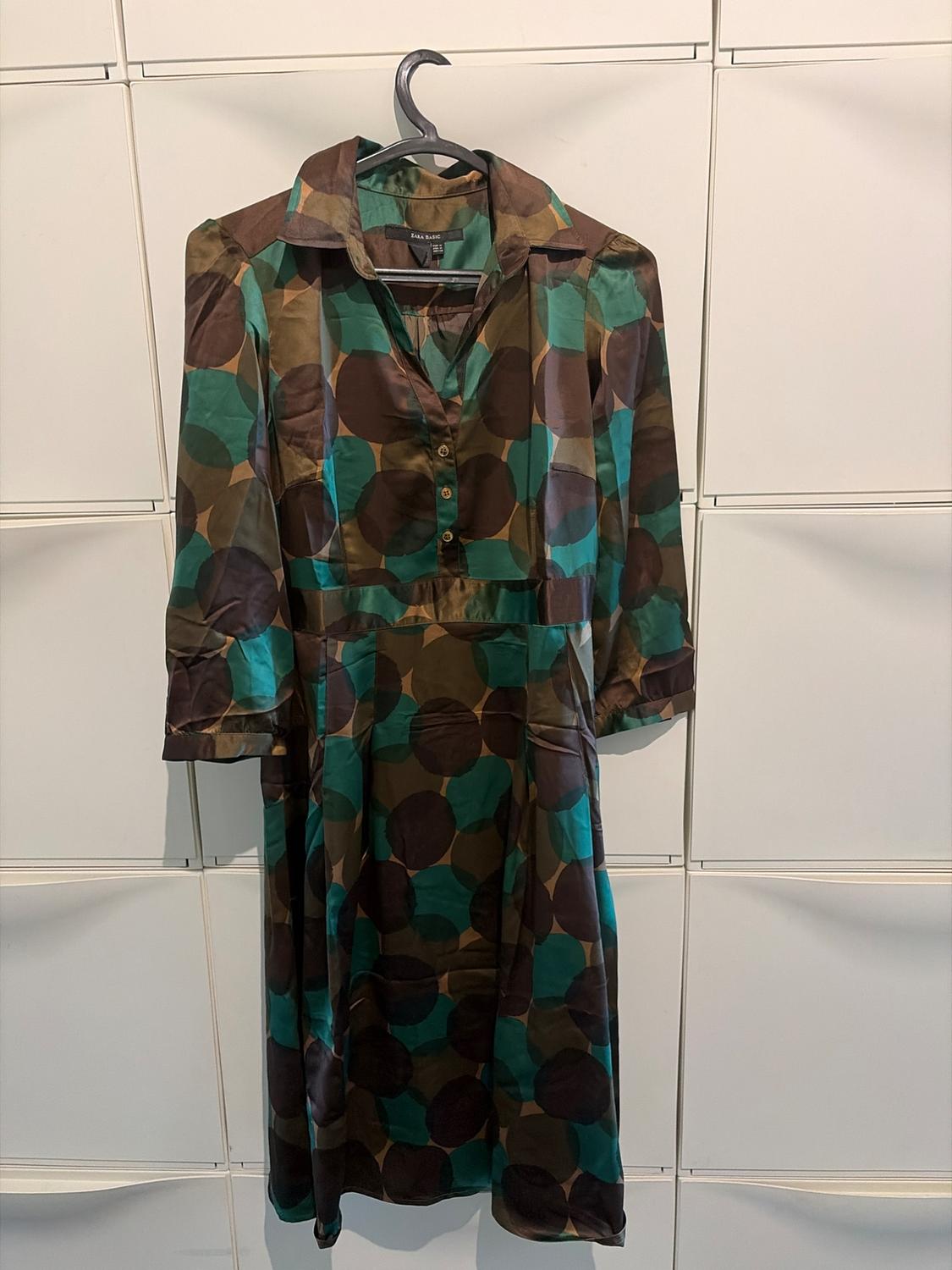 Πουκάμισο φόρεμα Zara Basic με στάμπα από μεγάλα πουά σε καφέ και πράσινες αποχρώσεις, μανίκι τριών τετάρτων, κρεμασμένο σε μια κρεμάστρα.