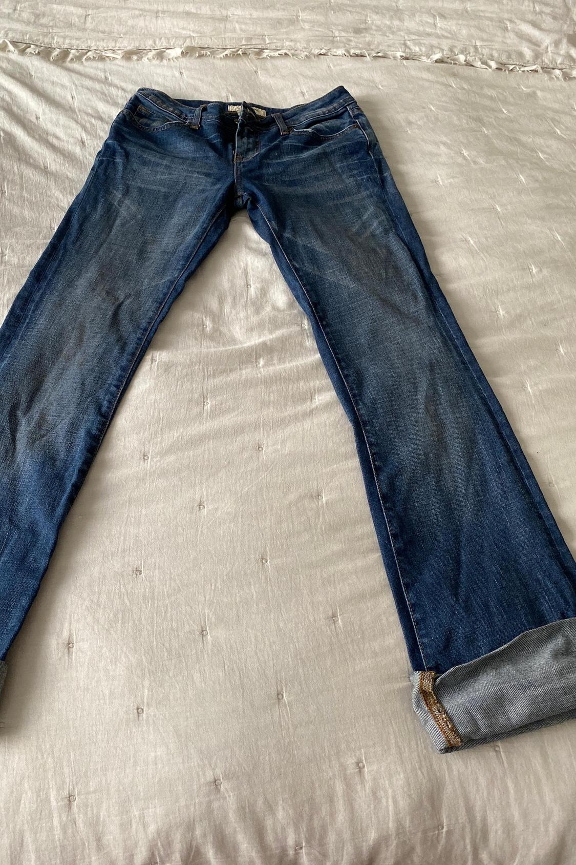 Front view of blue jeans with distressed effect and hem.