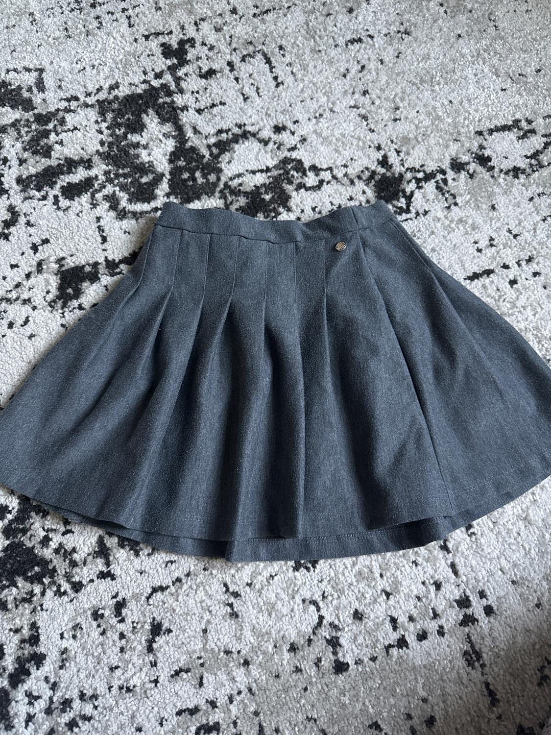 Grey pleated skirt on a black and white abstract design rug.