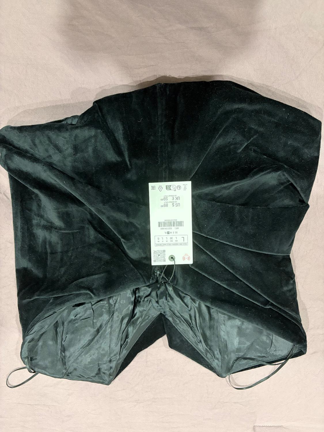 Black fabric bag on a beige background, with a visible tag showing sizes US S, UK 6, EU 34 and price $89.90.